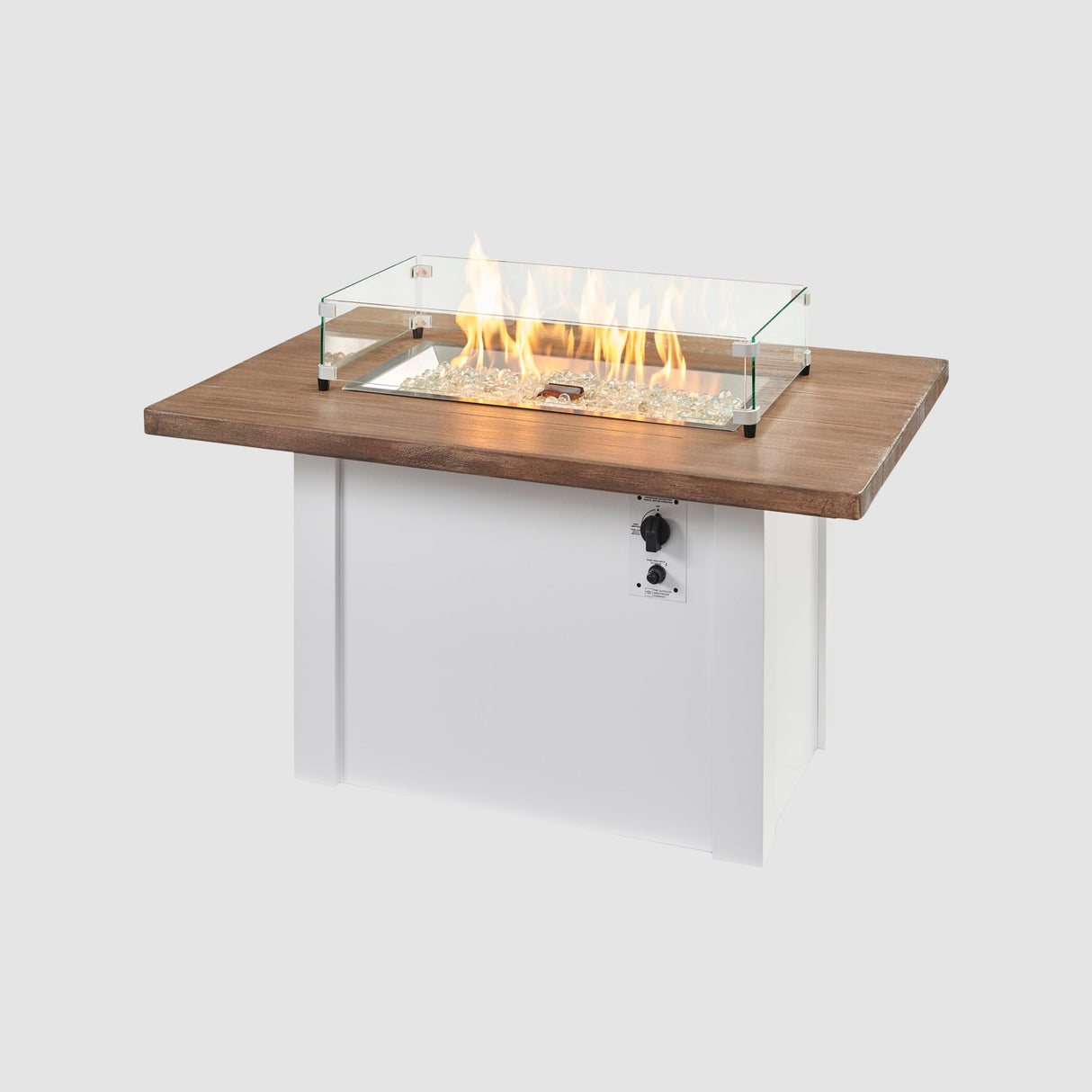 A glass wind guard placed on the top of a Havenwood Rectangular Gas Fire Pit Table with a Driftwood top and White base