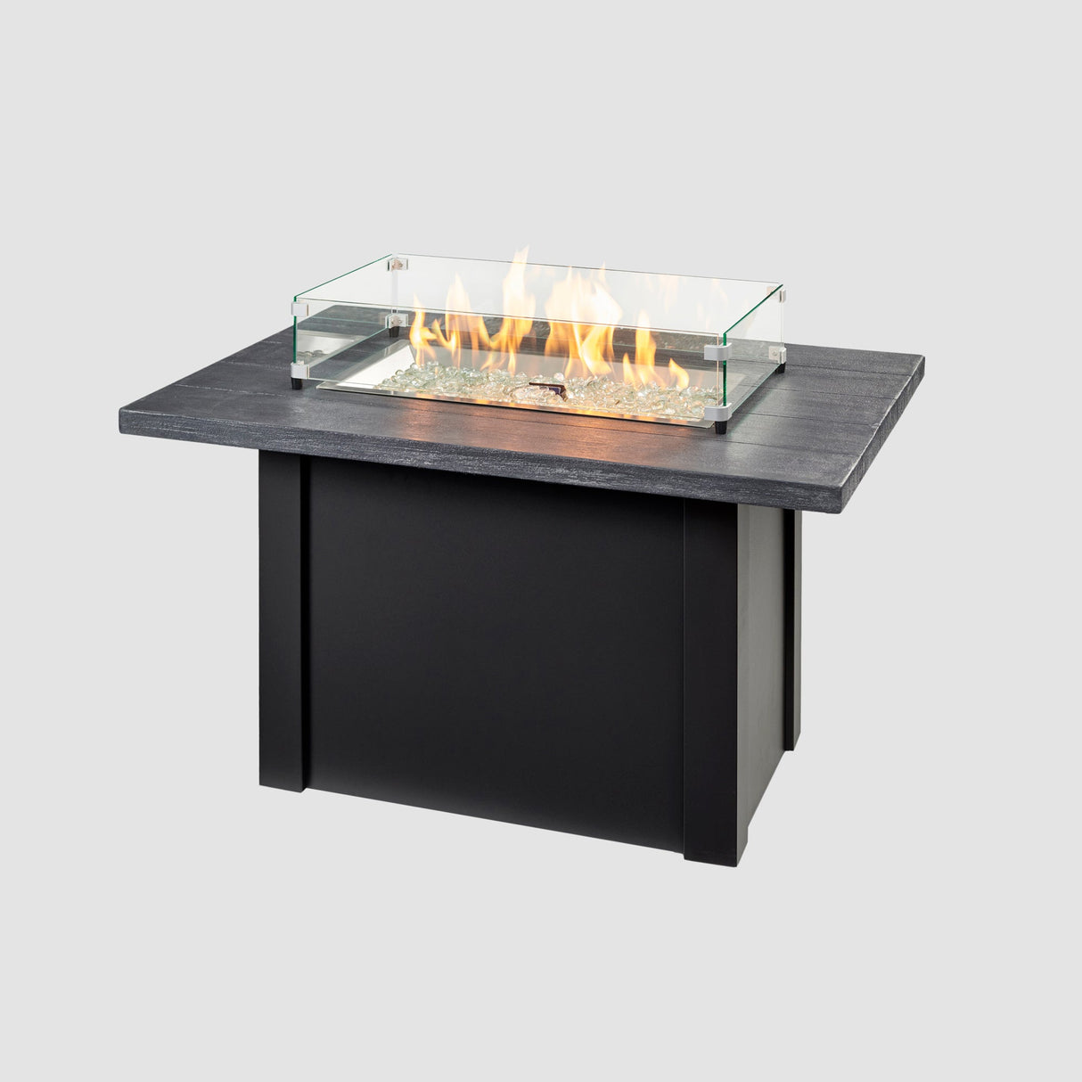 A glass wind guard placed on the top of a Havenwood Rectangular Gas Fire Pit Table with a Carbon Grey top and Luverne Black base