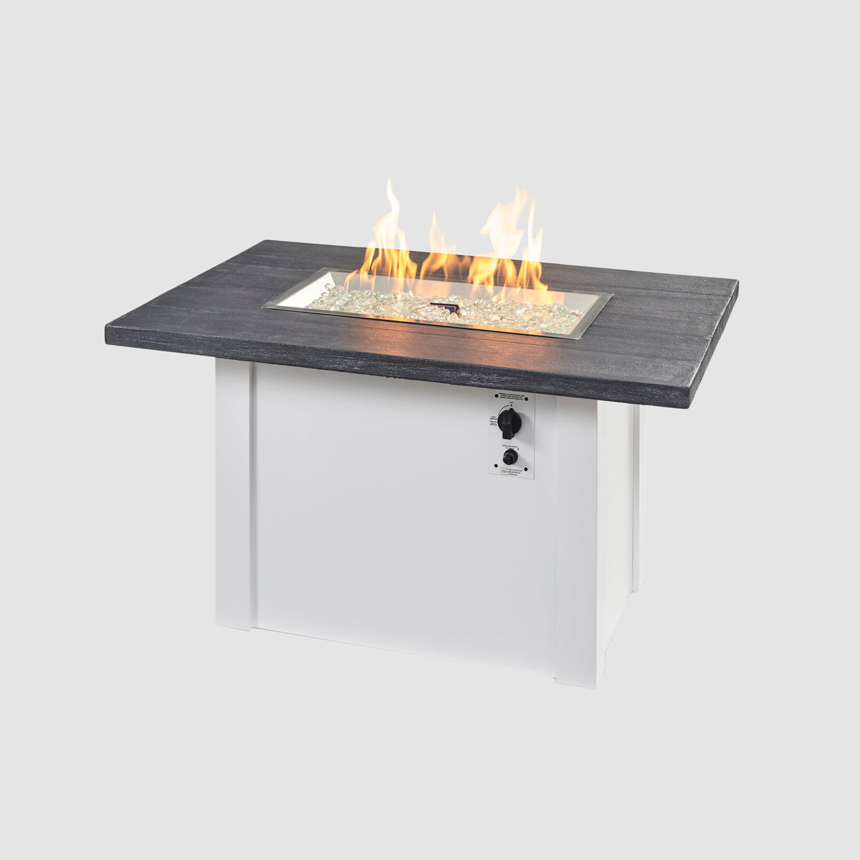 A large flame coming off the burner of a Havenwood Rectangular Gas Fire Pit Table with a Carbon Grey top and White base