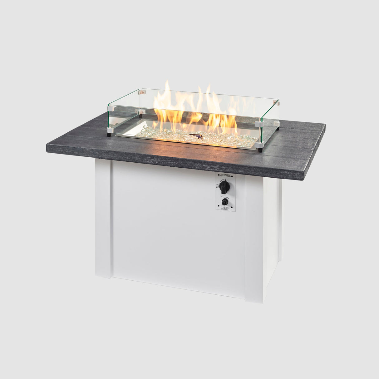A glass wind guard on top of a Havenwood Rectangular Gas Fire Pit Table with a Carbon Grey top and White base