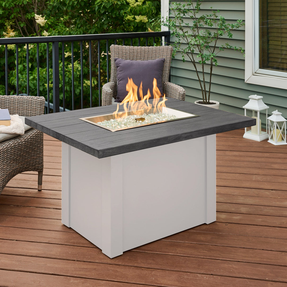 The Havenwood Rectangular Gas Fire Pit Table with a Carbon Grey top and White base on an outdoor patio setup