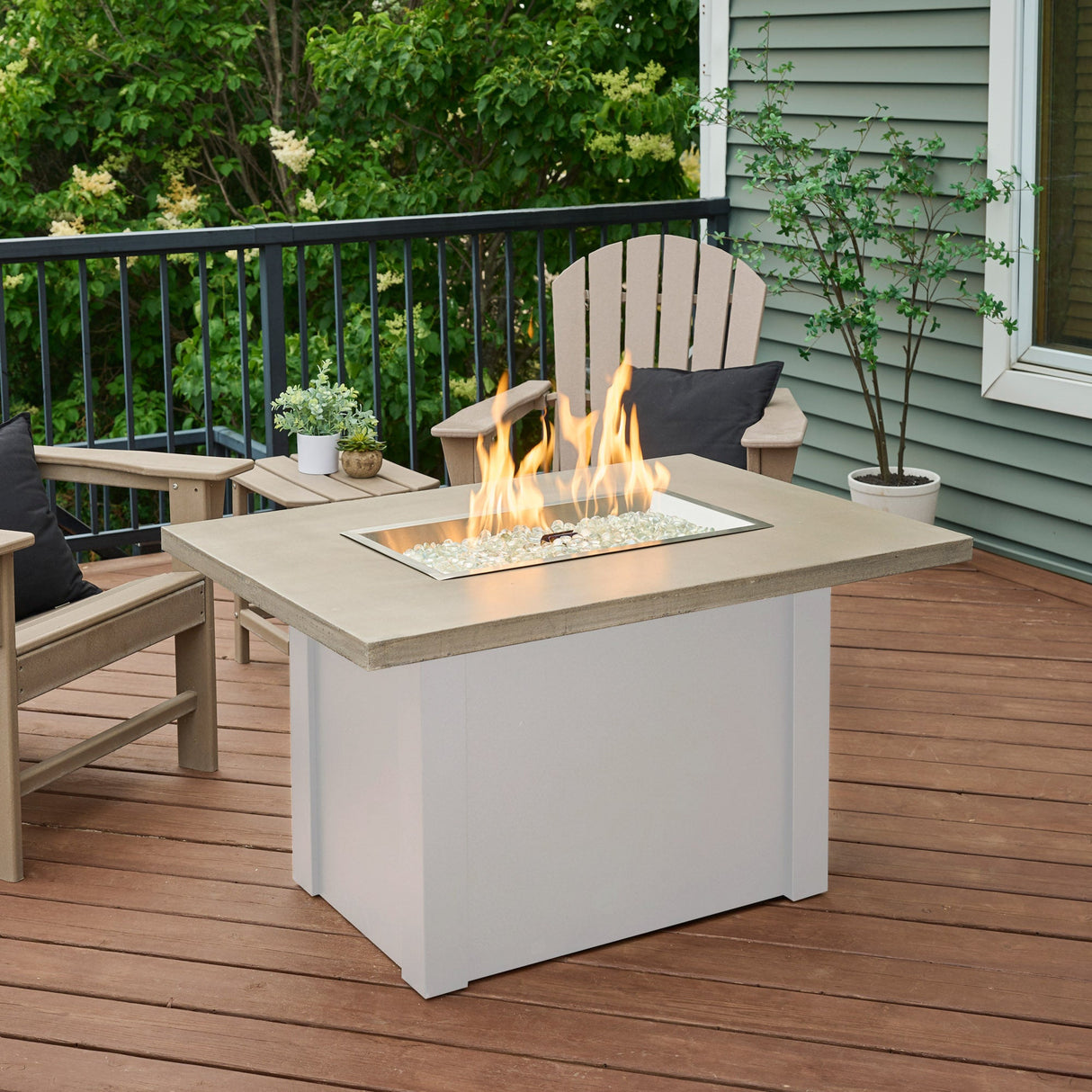 The Havenwood Rectangular Gas Fire Table with a Pebble Grey top and White base being used on an outdoor deck setup