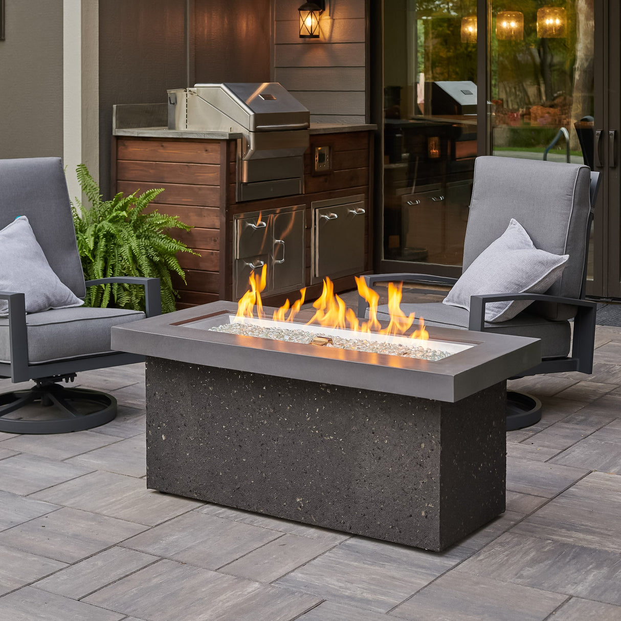 Midnight Mist Key Largo Linear Gas Fire Pit Table outside and surrounded by patio furniture