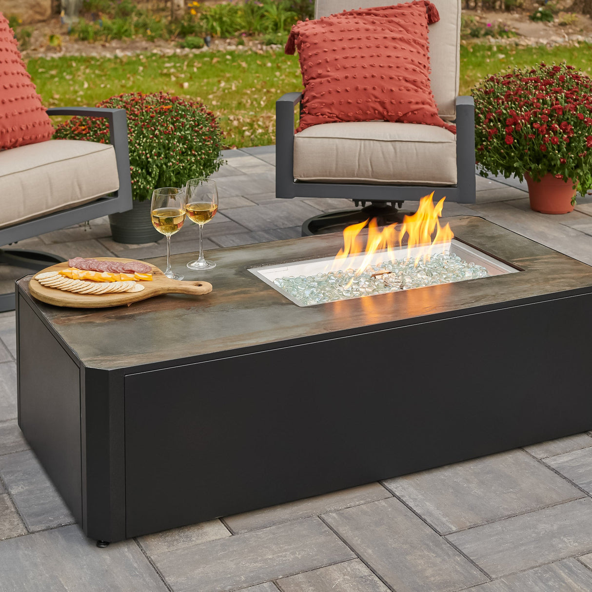 The Kinney Rectangular Gas Fire Pit Table being used as a table with food and drink outside