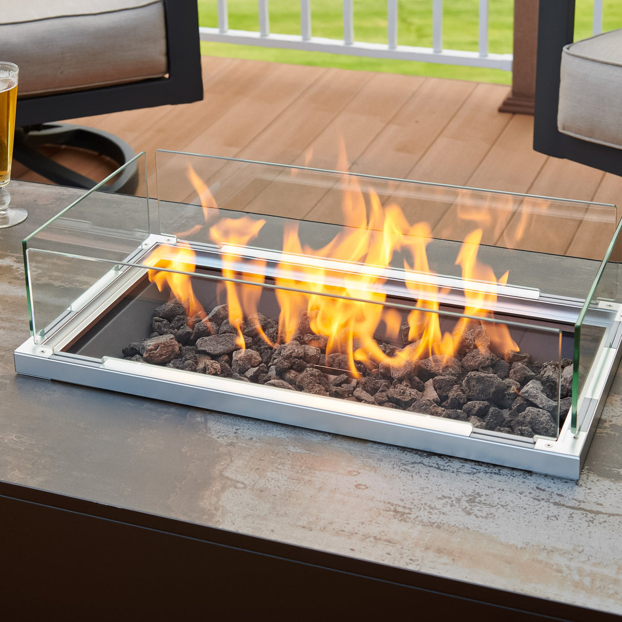 Close up of the folding glass wind guard being used on the Kinney Rectangular Gas Fire Pit Table