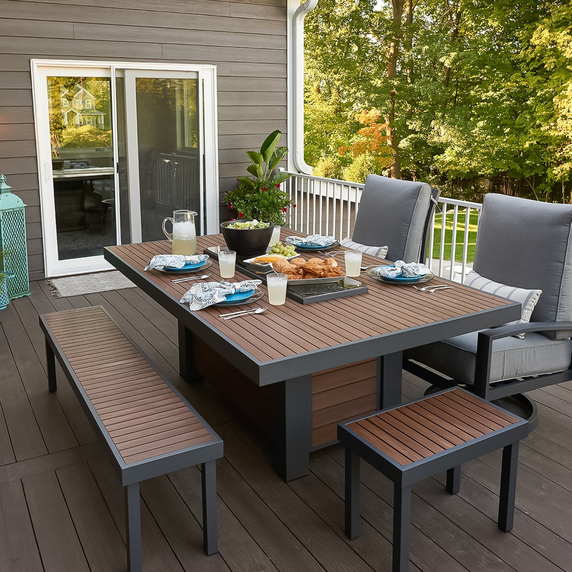 A cover placed on the Kenwood Linear Dining Height Gas Fire Pit Table with food and drink placed on the top