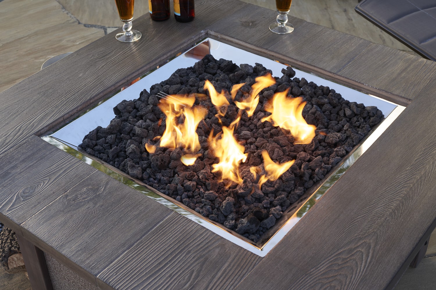A close up view of black lava rocks in a square fire pit table