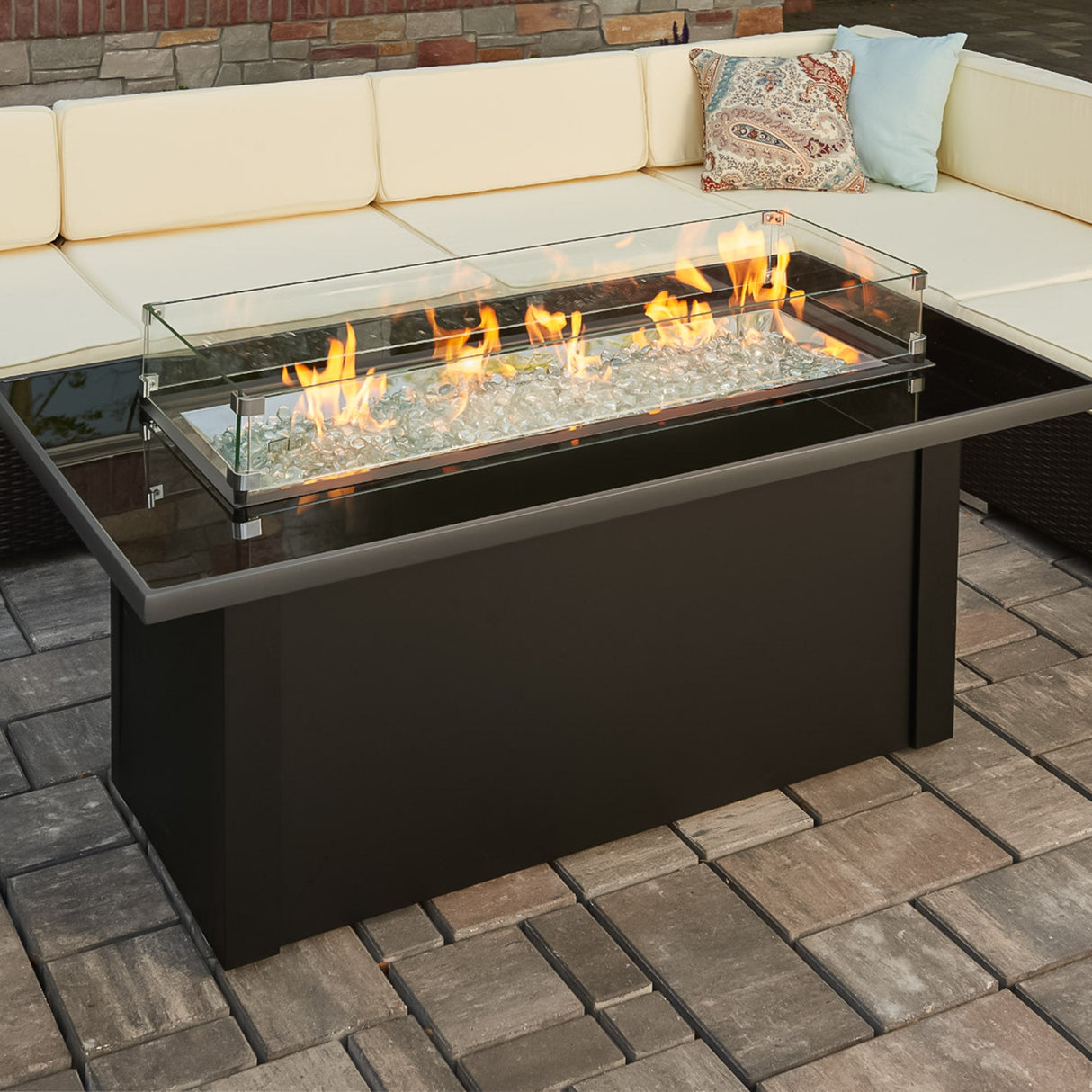 A glass wind guard placed on top of the Monte Carlo Linear Gas Fire Pit Table to protect the flame from the wind