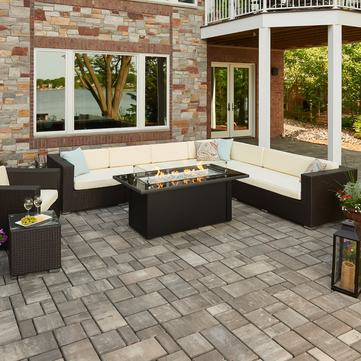 A patio that has a Monte Carlo Linear Gas Fire Pit Table, L-Shaped outdoor couch, and other decorations