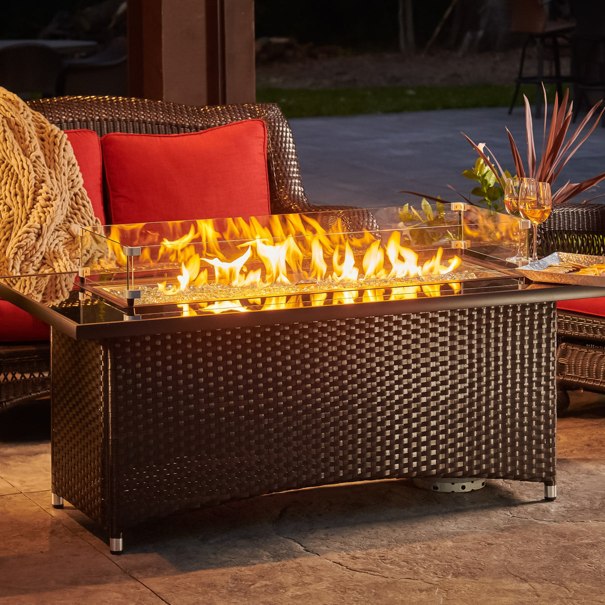 A close up view of a glass wind guard and the flame coming from the Montego Linear Gas Fire Pit Table