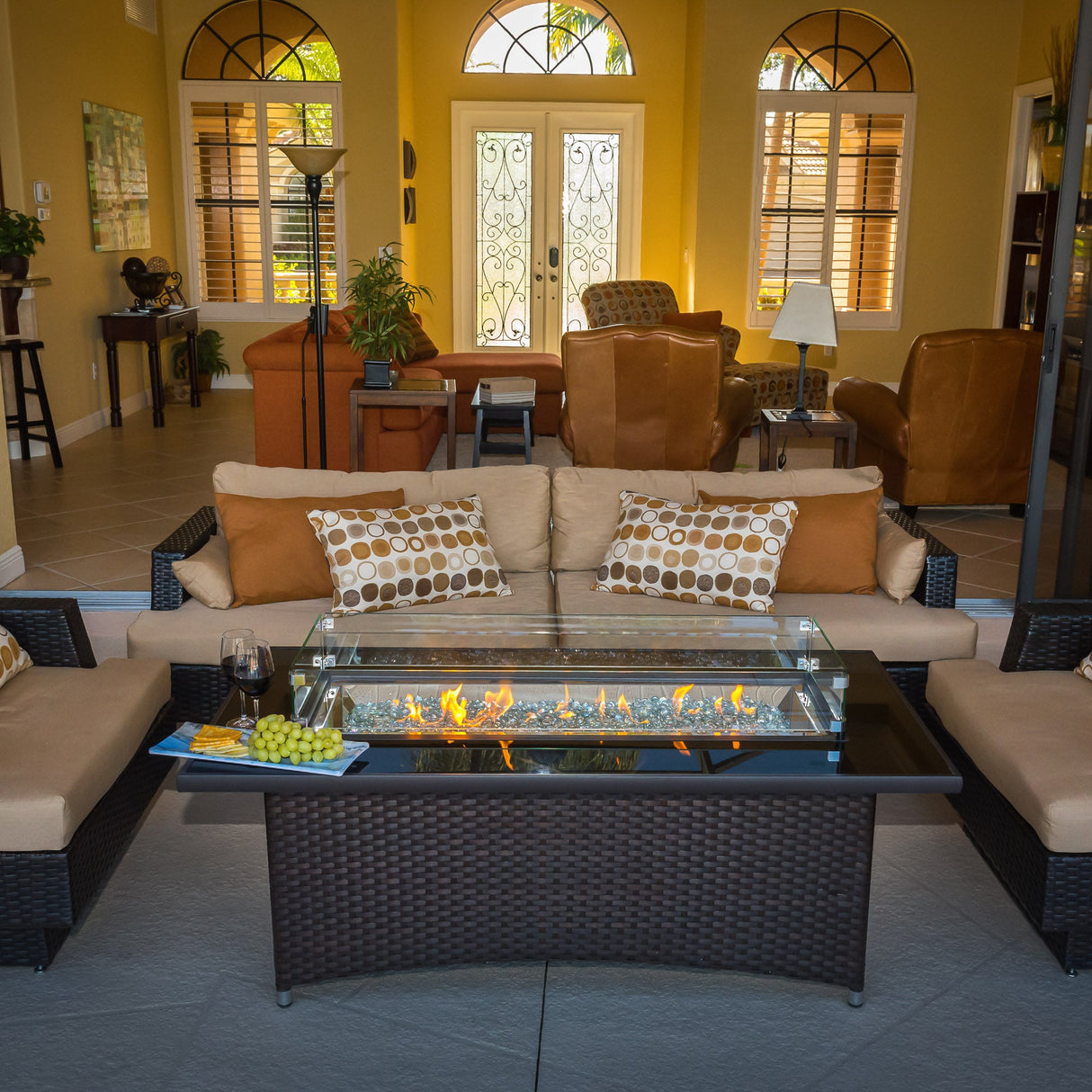 A view of a back porch that is accompanied by a Montego Linear Gas Fire Pit Table and matching patio furniture