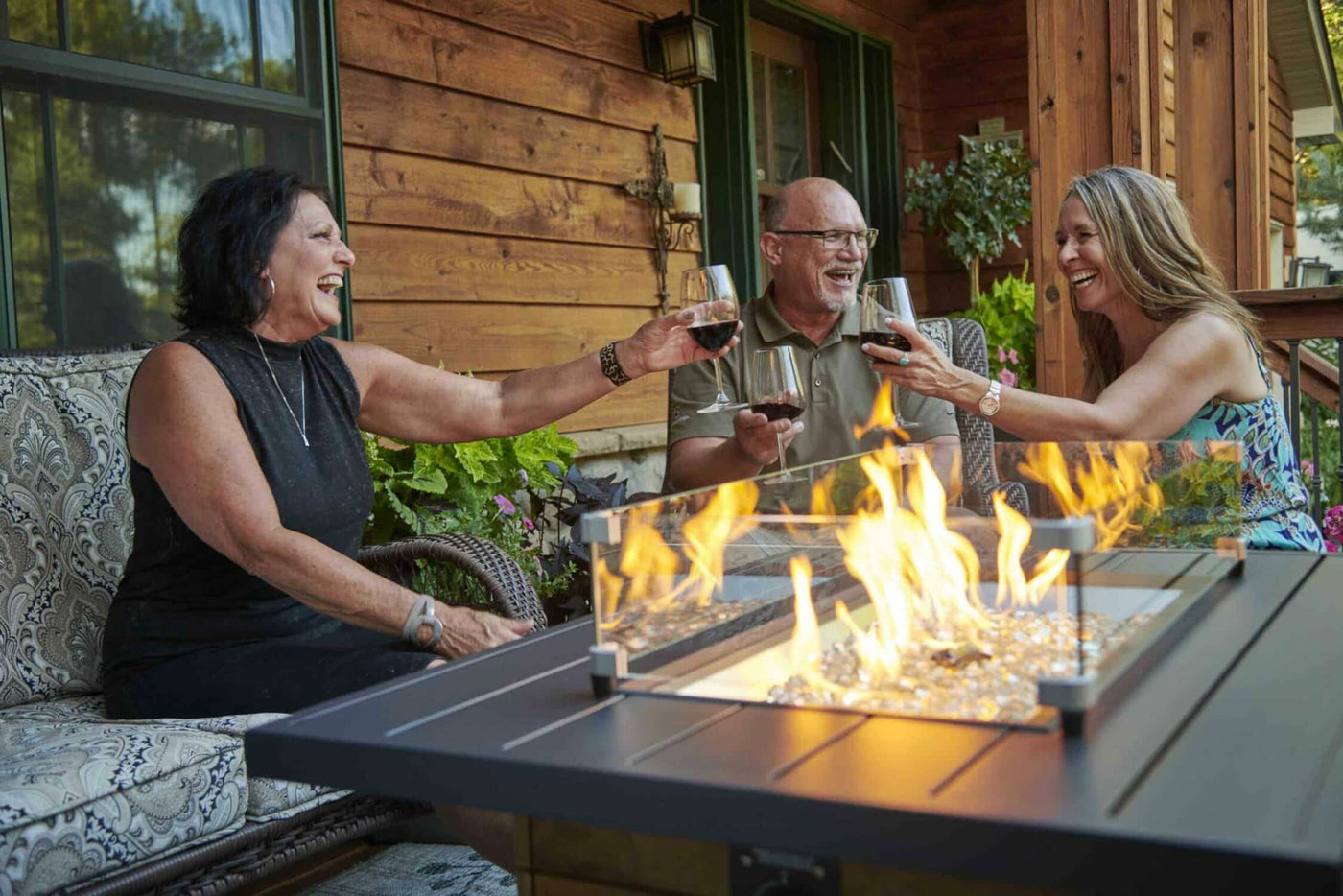 Three individuals enjoying a drink around a Darien Rectangular Gas Fire Pit Table