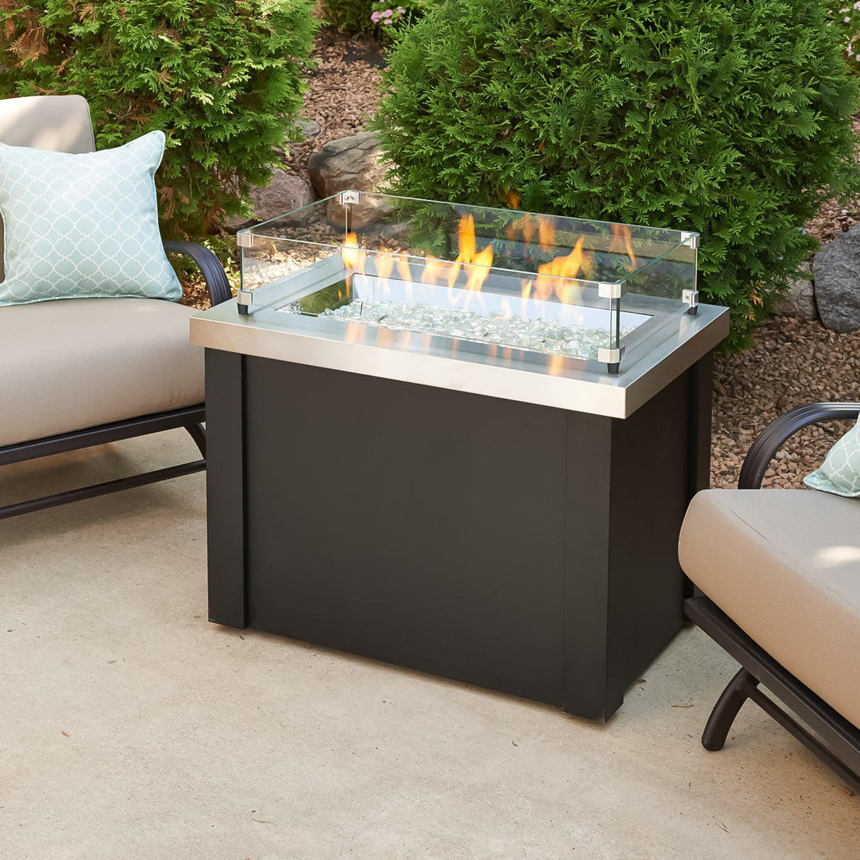 A glass wind guard placed on the Providence Rectangular Gas Fire Pit Table protecting the flame from the wind