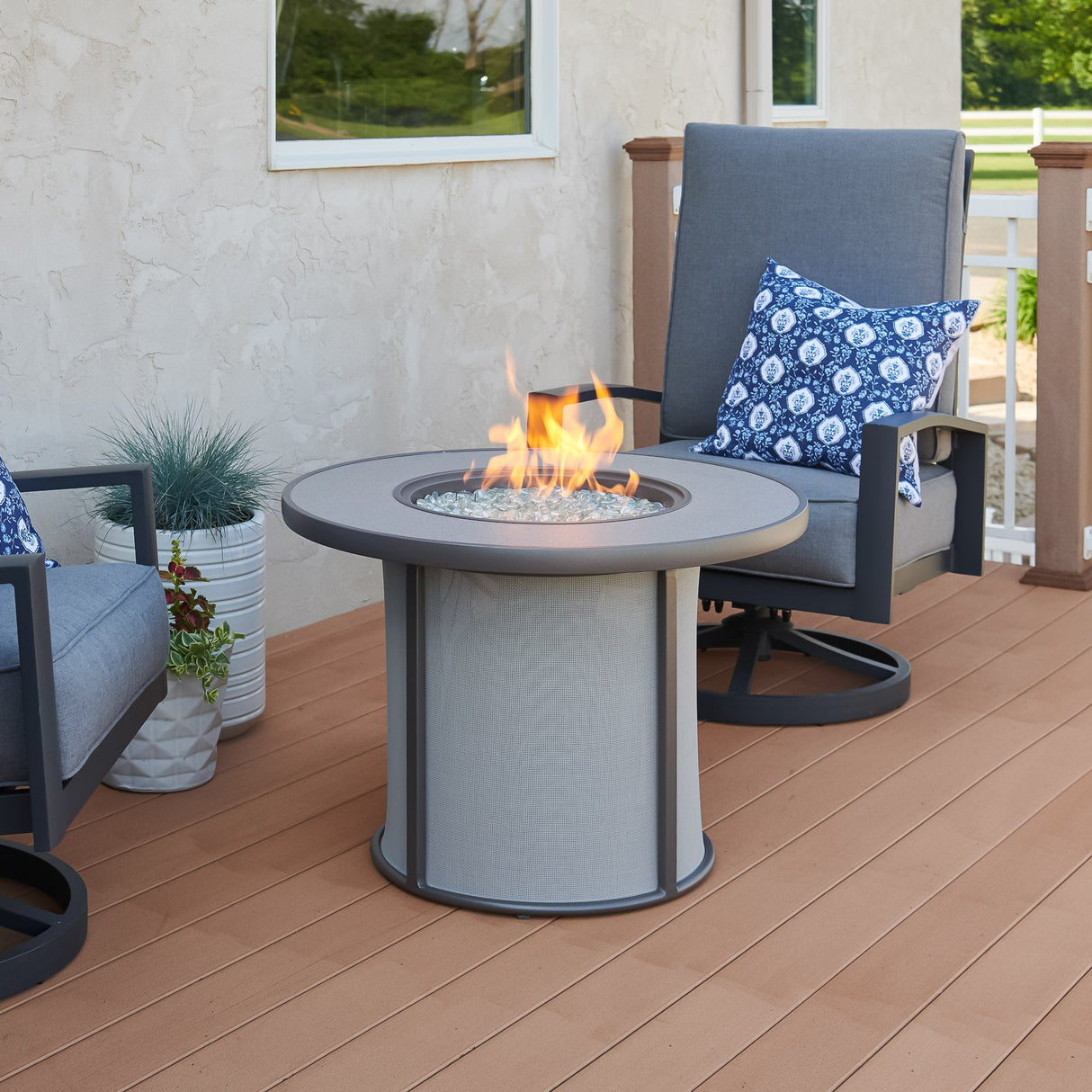 The Grey Stonefire Round Gas Fire Pit Table on an outdoor patio