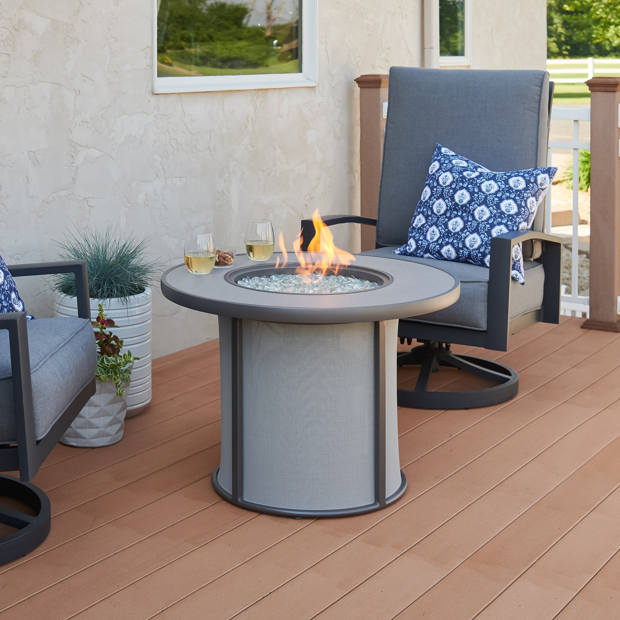 The Grey Stonefire Round Gas Fire Pit Table being used as a table with food and drink on the edges