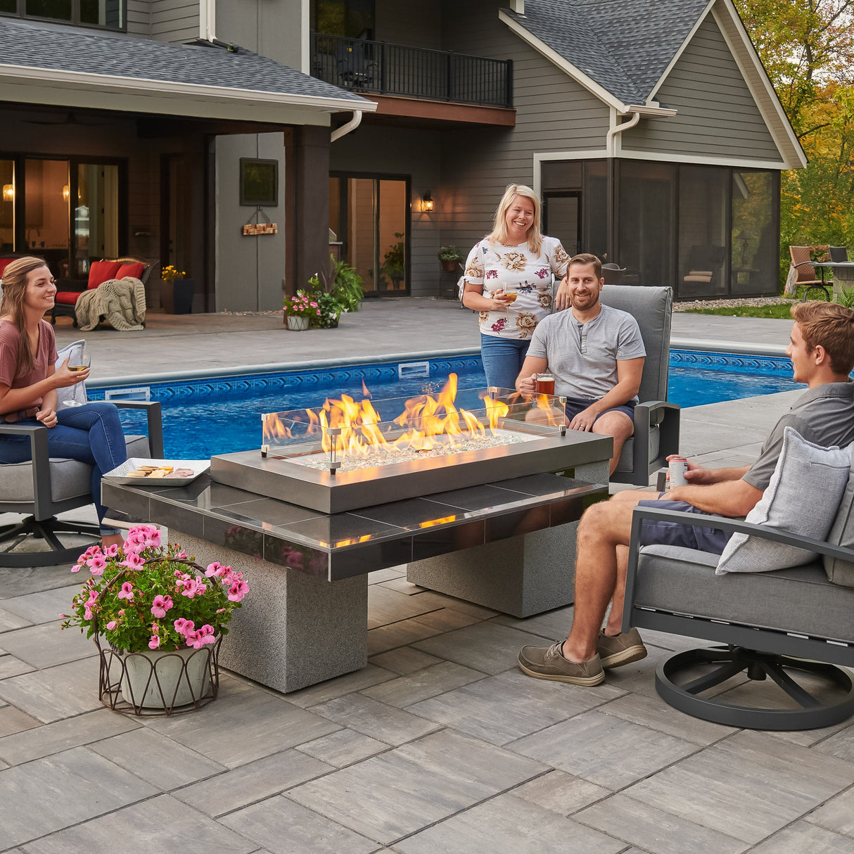 A group of individuals relaxing next to the Black Uptown Linear Gas Fire Pit Table and enjoying some food and drink