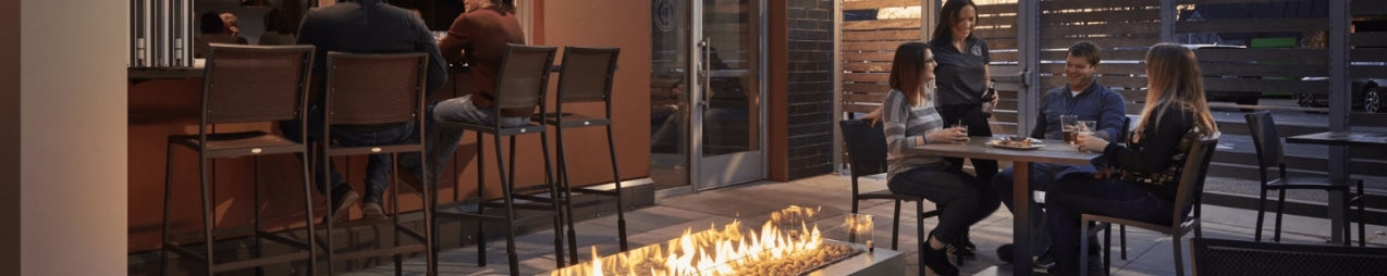 A group of friends sitting at a table next to a Cove Linear Gas Fire Pit Table