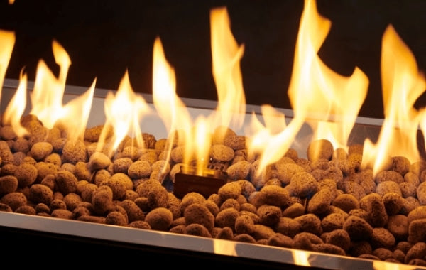 A close up view of lava rocks with a flame burning over them