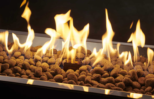 A close up view of the flame coming from a Crystal Fire burner with lava rocks on the burner