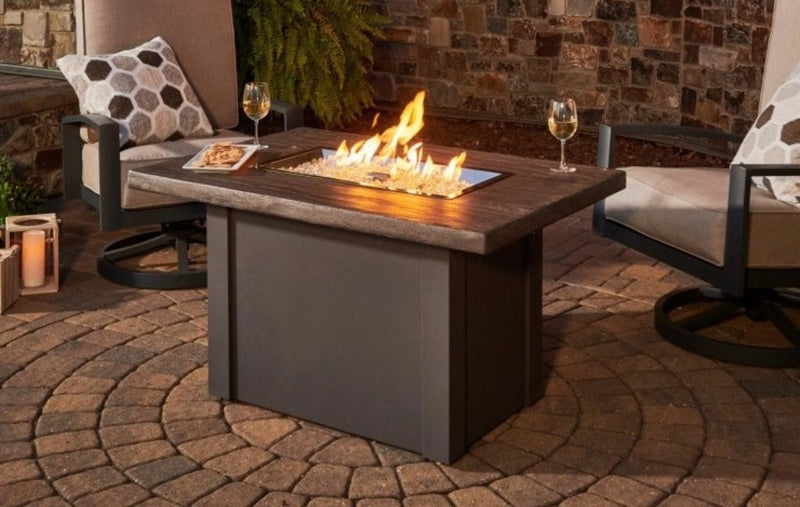 The Havenwood Rectangular Gas Fire Pit Table on an outdoor patio at night