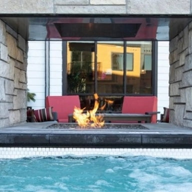 A custom linear gas fire pit table next to a pool
