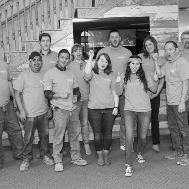 Outdoor GreatRoom Company employees posing for a photograph next to a fireplace mantel