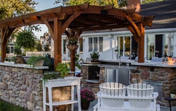 A pergola setup behind a house with a large outdoor kitchen