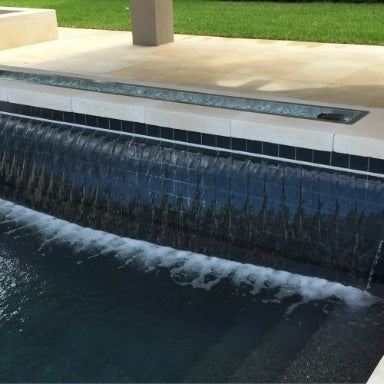 A view of the side of a pool next to a patio setup