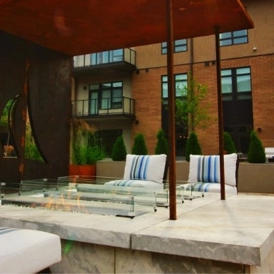 A rustic outdoor setting with a linear fire pit table and patio furniture