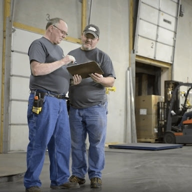 Two individuals working on a warehouse loading dock